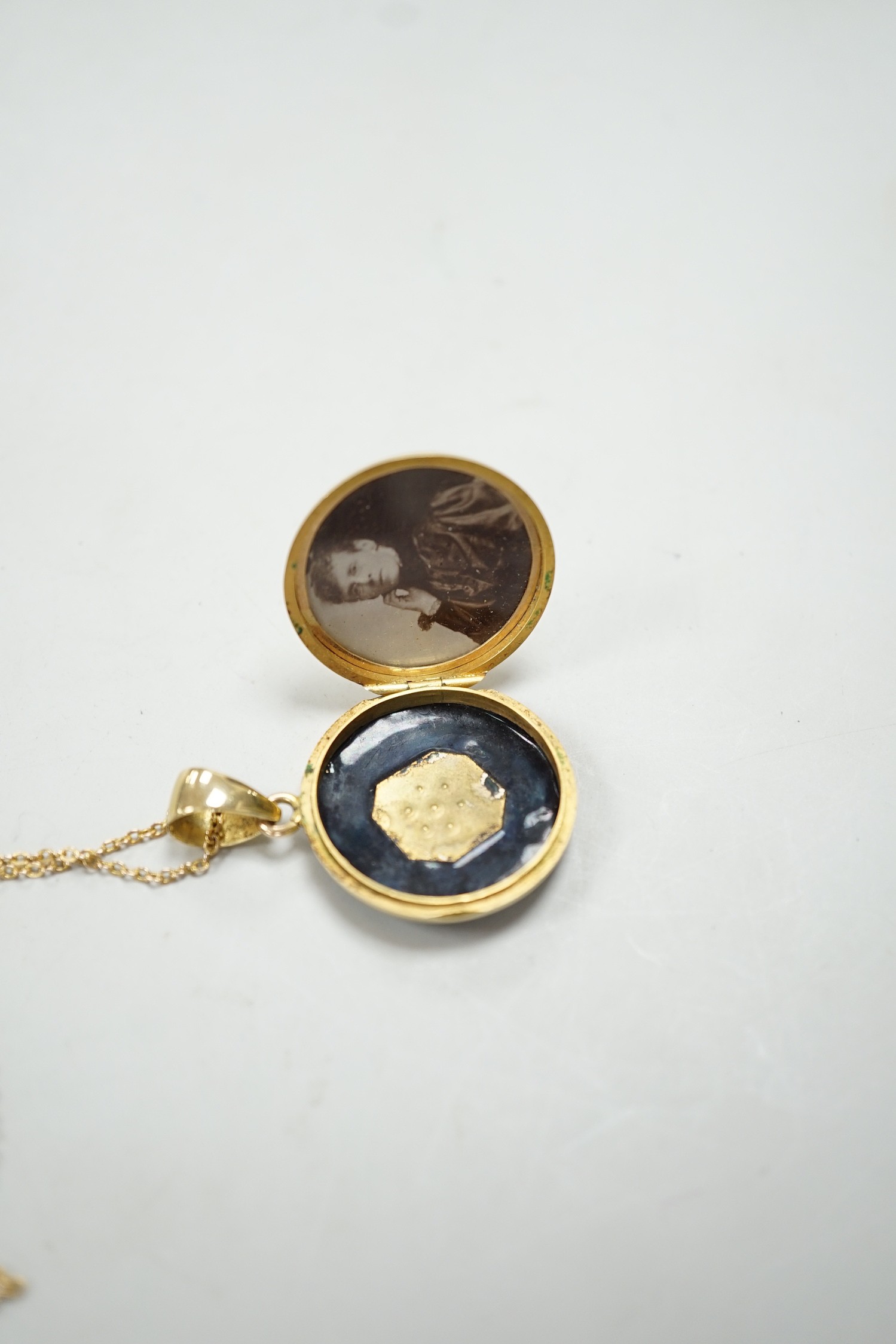 A late Victorian 15ct, black enamel and seed pearl set circular mourning locket, diameter 23mm, on a 9ct fine link chain, 40cm, gross weight 10 grams.